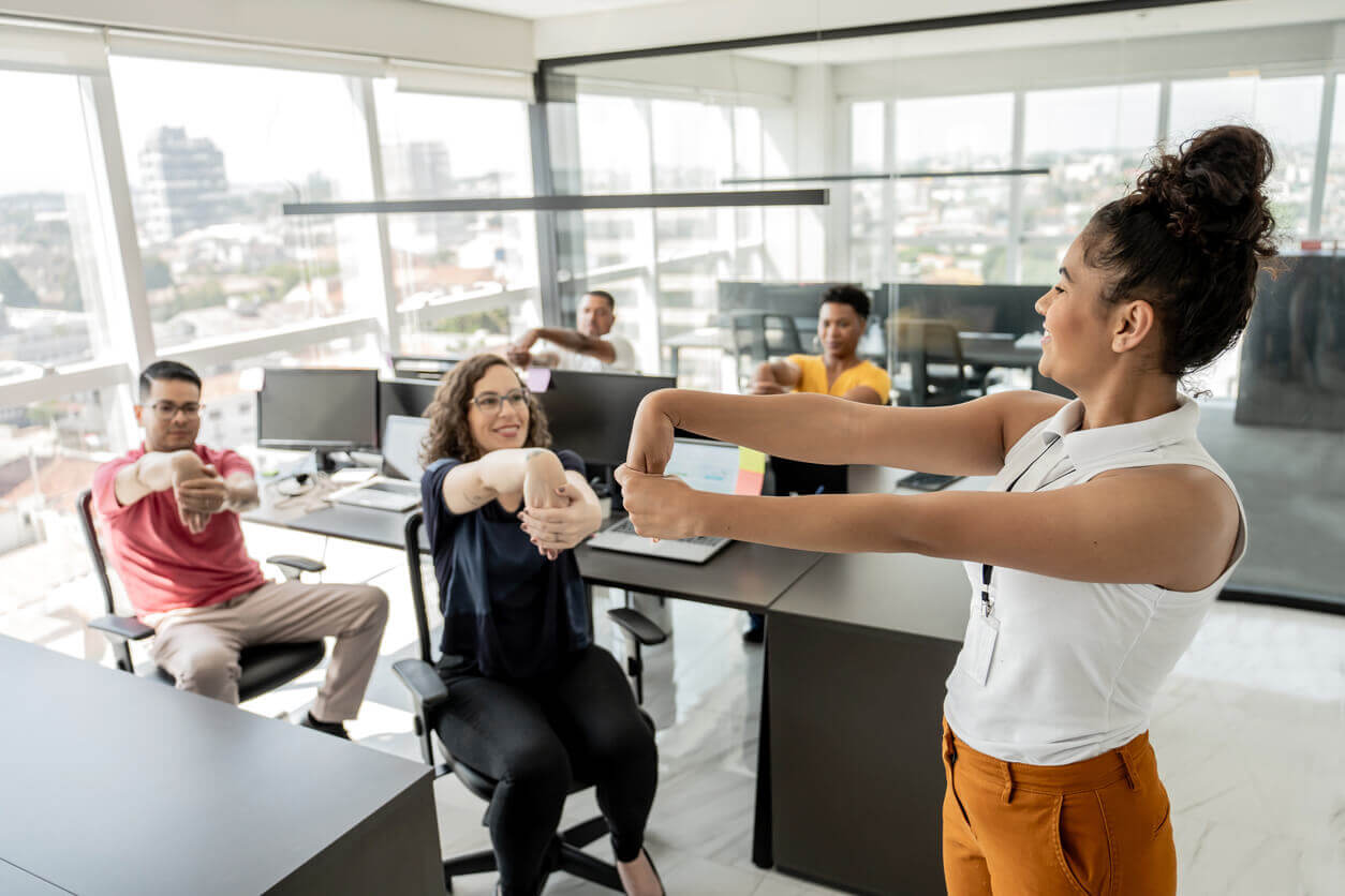 Colaboradores fazendo alongamento no escritório em ação de cuidado com a saúde mental no trabalho.