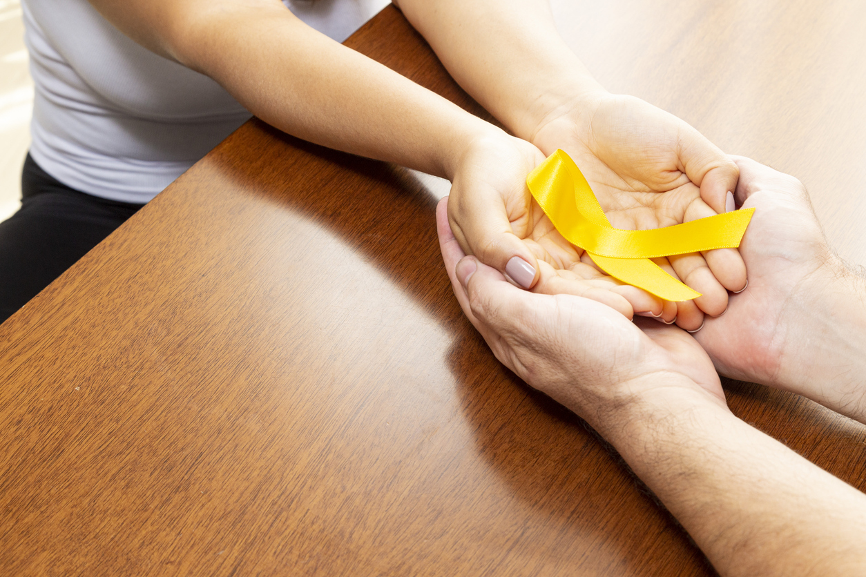Mãos segurando laço amarelo em representação ao Setembro Amarelo e ao cuidado com a saúde mental.